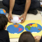 Students watch a teacher compare hemisphere to plenisphere maps