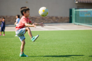 Boy with dark hair kicks soccer ball